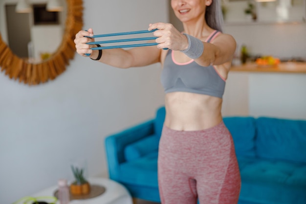 Mujer haciendo ejercicio con banda de resistencia en el brazo en casa