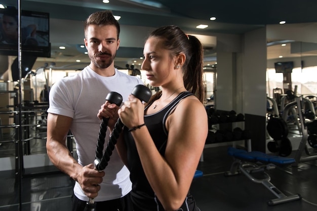 Mujer haciendo ejercicio de bíceps con su entrenador personal