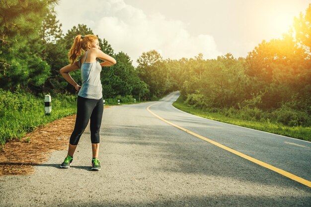 Mujer haciendo ejercicio en la carretera contra el cielo