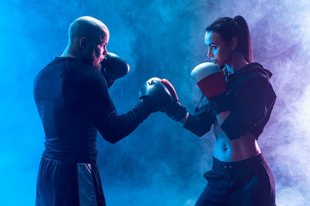 Mujer haciendo ejercicio con entrenador en la lección de boxeo y defensa personal