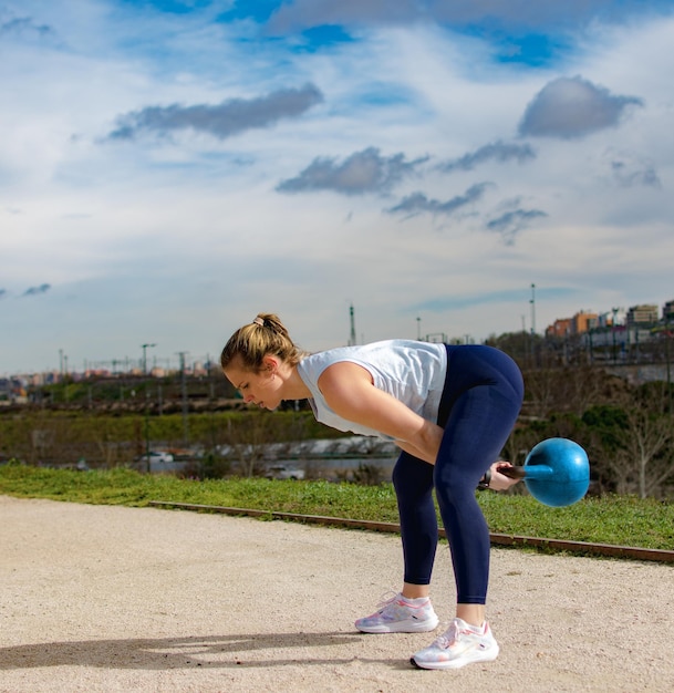 Mujer haciendo ejercicio con un kettlebell al aire libre