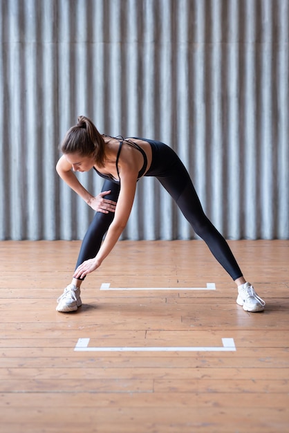 Mujer haciendo ejercicio de pie doblando hacia adelante estiramientos de piernas y espalda baja