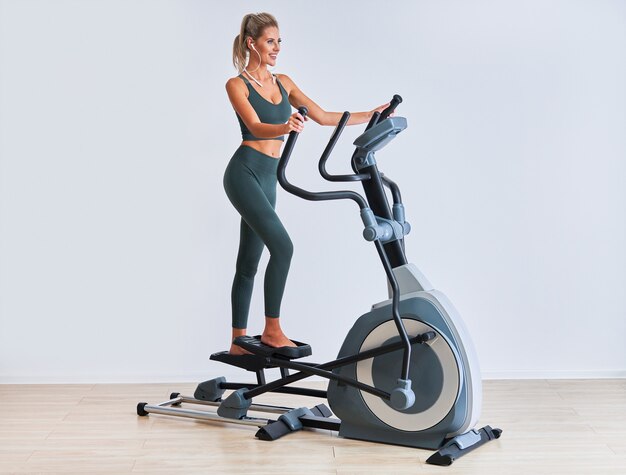 Mujer haciendo ejercicio en x-trainer en fitness studio