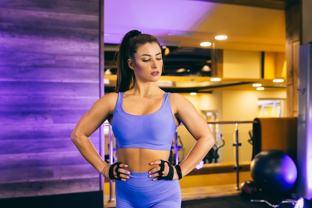 Mujer haciendo ejercicios deportivos y posando para la cámara en el gimnasio.