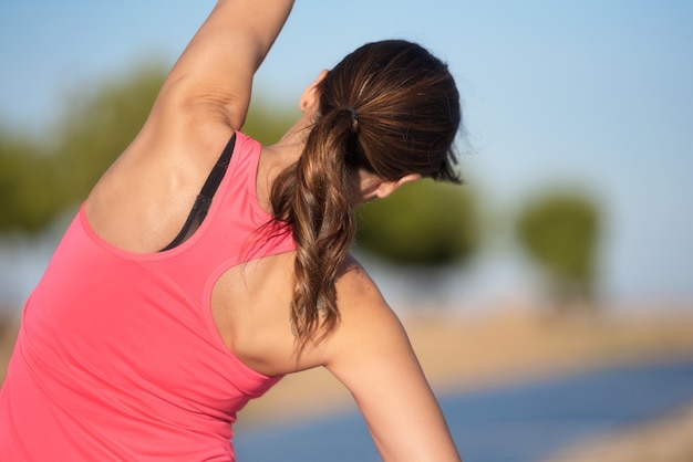 Foto mujer haciendo ejercicios de estiramiento para espalda, fondo deportivo.