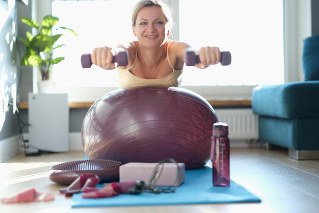 Mujer haciendo ejercicios con pesas en una pelota de deportes