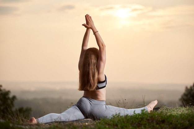 Mujer haciendo ejercicios de yoga al aire libre al atardecer