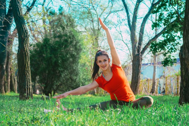 Mujer haciendo ejercicios de yoga en pasto verde