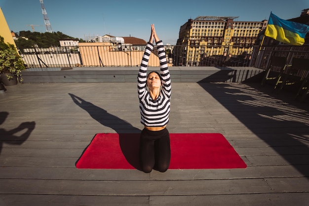 Mujer haciendo ejercicios de yoga en el techo de la casa temprano en la mañana