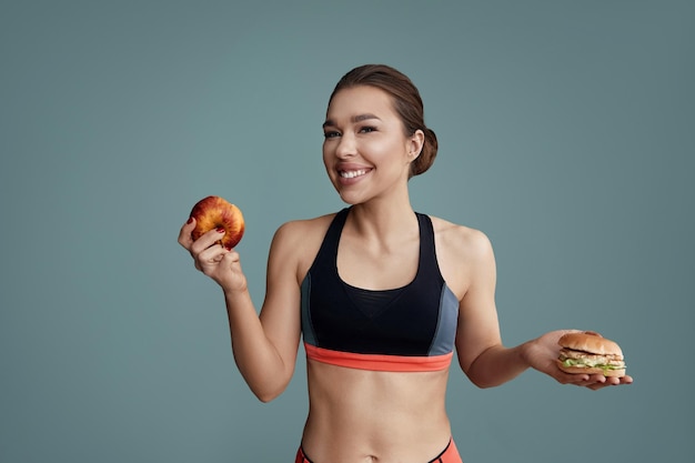 Mujer haciendo elección entre manzana y hamburguesa Concepto de dieta Alimentación saludable