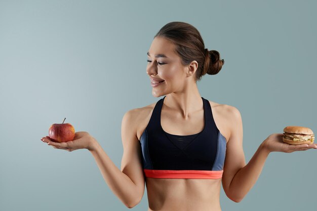 Mujer haciendo elección entre manzana y hamburguesa Concepto de dieta Alimentación saludable