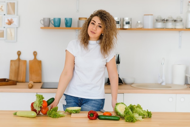 Foto mujer haciendo ensalada en la cocina.