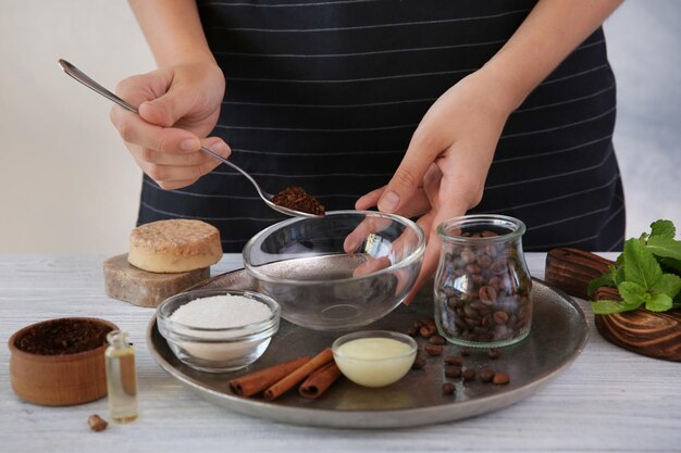 Mujer haciendo exfoliante corporal de café en la mesa de madera