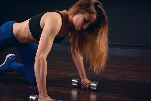 Mujer haciendo flexiones con pesas