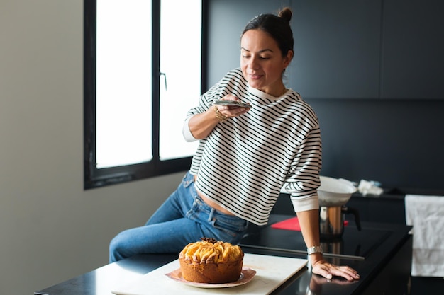 Mujer haciendo una foto para una red social mientras cocina pastel