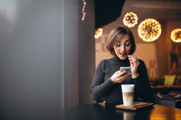 Mujer haciendo fotos de un café en un café