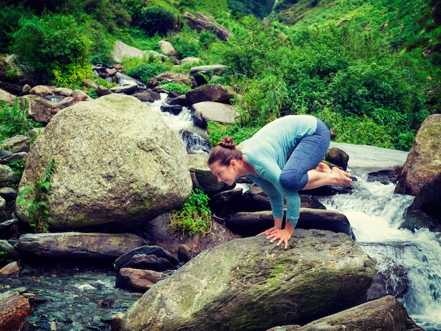 Mujer haciendo Kakasana asana equilibrio del brazo en cascada