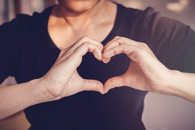 Mujer haciendo las manos en señal de forma de corazón, seguro médico, concepto de voluntario de donación