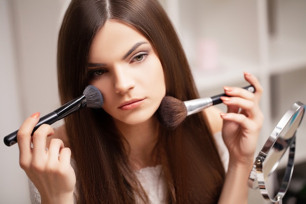 mujer haciendo maquillaje en casa delante del espejo