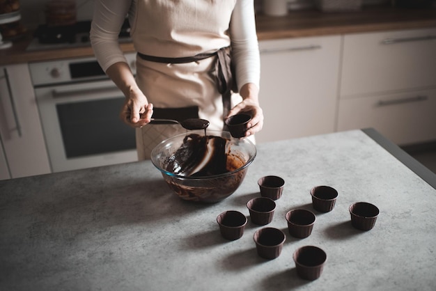 Mujer haciendo masa de chocolate para muffins en casa