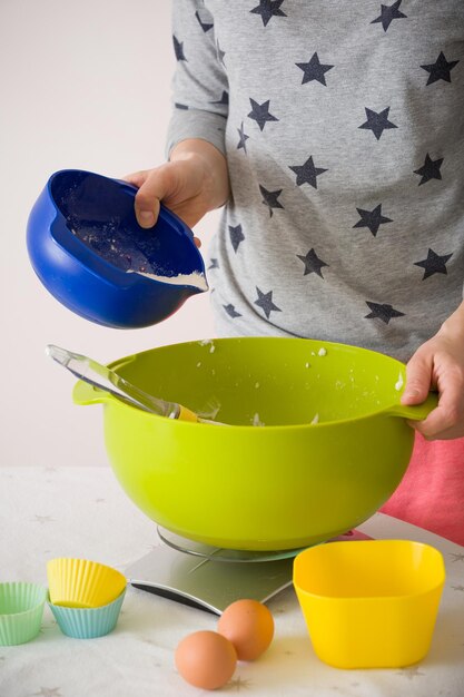 Mujer haciendo masa para muffins Mezclando harina azúcar huevos y otros ingredientes de coloridos tazones Comida casera