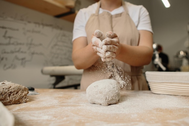 Mujer haciendo masa de pan francés casera Espolvoreando harina sobre la masa que está sobre una encimera