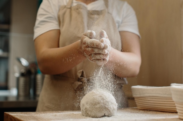 Mujer haciendo masa de pan francés casera Espolvoreando harina sobre la masa que está sobre una encimera