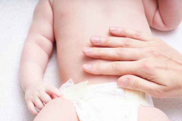 Mujer haciendo masaje contra barriga cólico al bebé