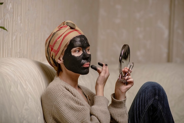 Mujer haciendo mascarilla de arcilla negra en casa