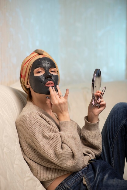 Mujer haciendo mascarilla de arcilla negra en casa