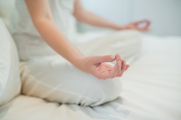 Mujer haciendo meditación en la cama en el dormitorio