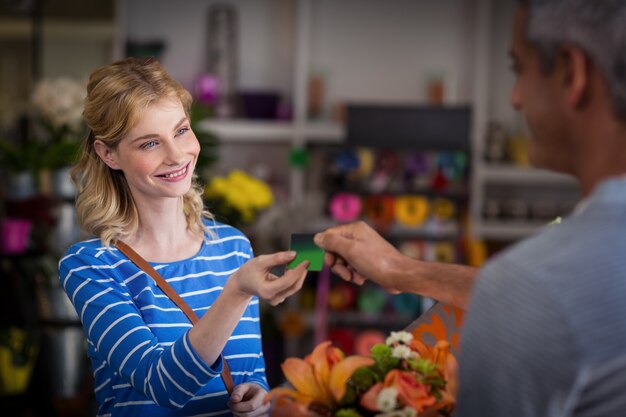 Mujer haciendo el pago con su tarjeta de crédito a floristería