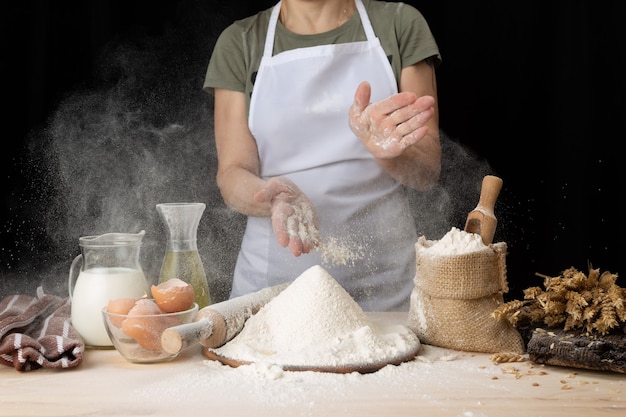 Mujer haciendo Pascua para hornear en panadería casera. Mujer preparando masa de pan sobre una mesa de madera en una panadería cercana