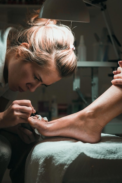 Mujer haciendo pedicura a un cliente en el salón