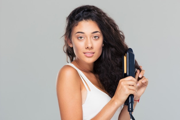 Mujer haciendo peinado con plancha de pelo