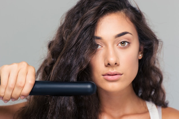 Mujer haciendo peinado con plancha de pelo