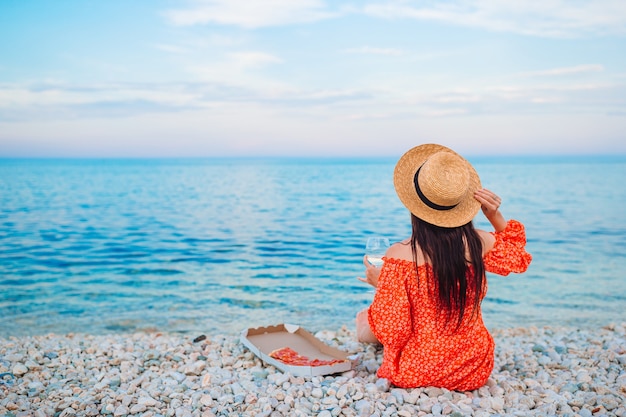 Mujer haciendo un picnic con pizza en la playa