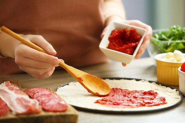 Mujer haciendo una pizza en una mesa de madera de cerca