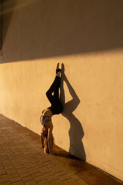 Una mujer haciendo una pose de yoga en una pared.