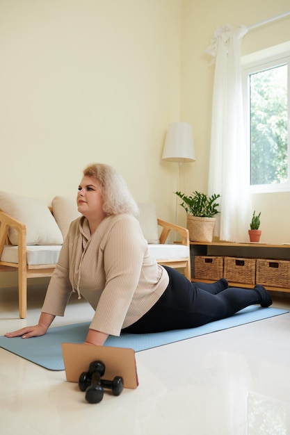 Mujer haciendo postura de yoga Cobra