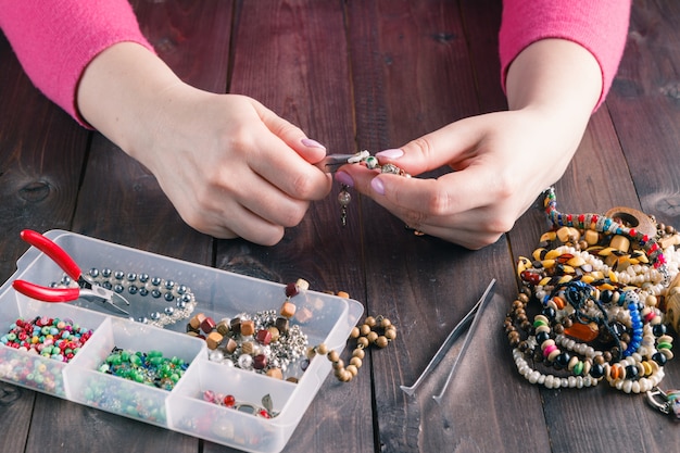 Mujer haciendo pulsera de cuentas con sus manos