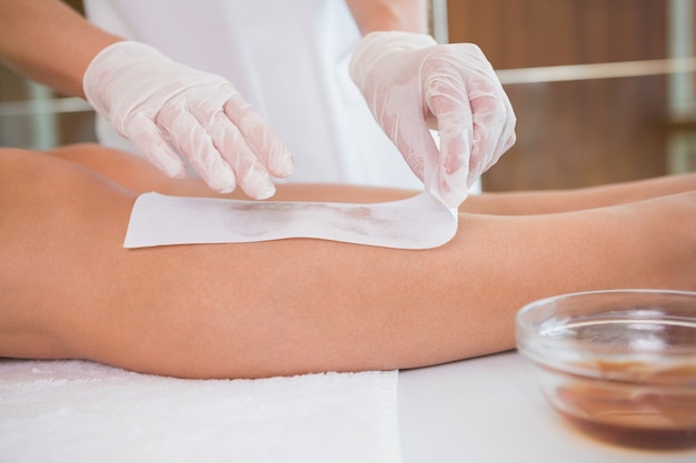 Mujer haciendo que sus piernas sean depiladas por un terapeuta de belleza