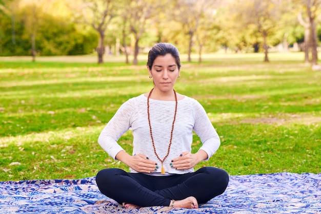 Mujer haciendo reiki y pose de yoga en una pose de chakra del parque