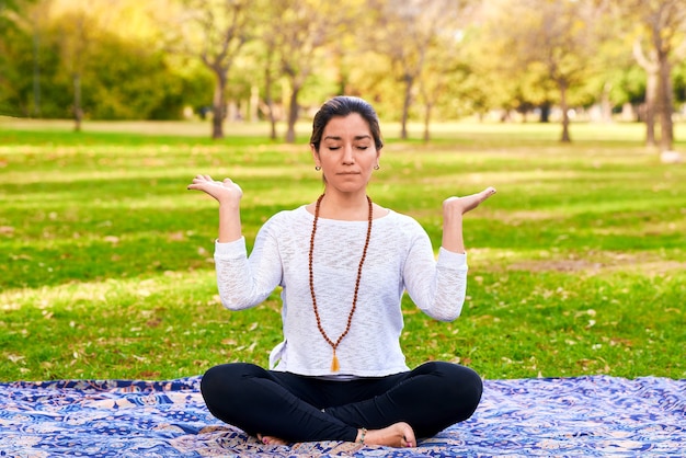 Mujer haciendo reiki y pose de yoga en una pose de chakra del parque