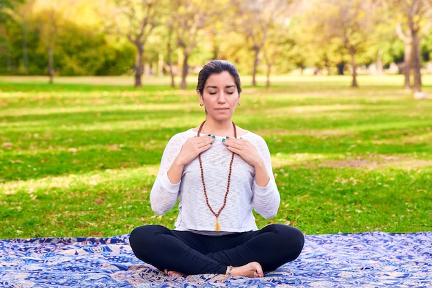 Mujer haciendo reiki y pose de yoga en una pose de chakra del parque