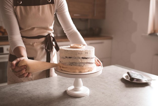 Mujer haciendo sabroso pastel con queso crema en la mesa de la cocina