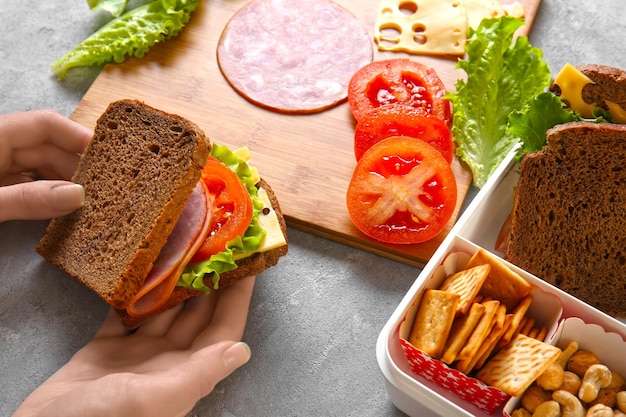 Mujer haciendo sabroso sándwich en la mesa