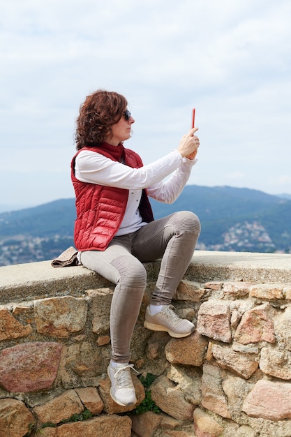 Mujer haciendo un selfie con su teléfono inteligente en la montaña