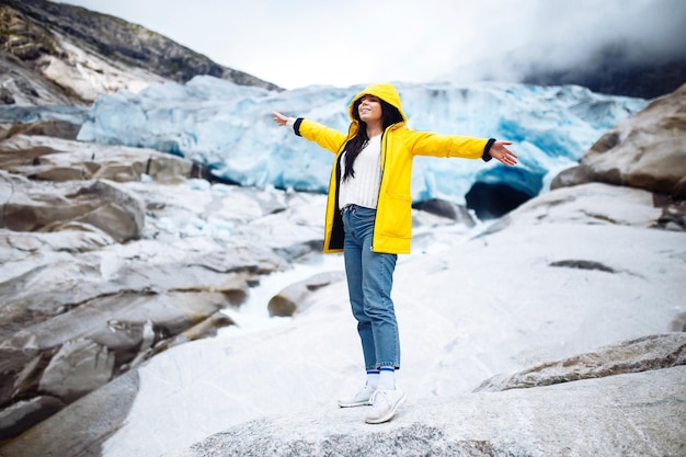 Mujer haciendo senderismo en el glaciar disfruta de la libertad Chica turista con chaqueta amarilla cerca del gran glaciar