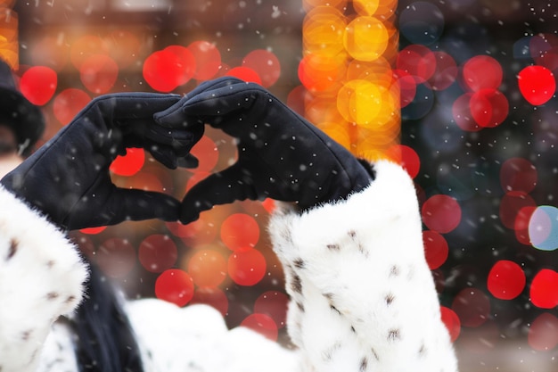 Mujer haciendo el signo del corazón de sus manos en la calle